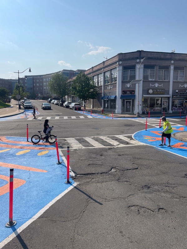 Street-level view of asphalt art intersection mural at S. Essex Ave., Orange