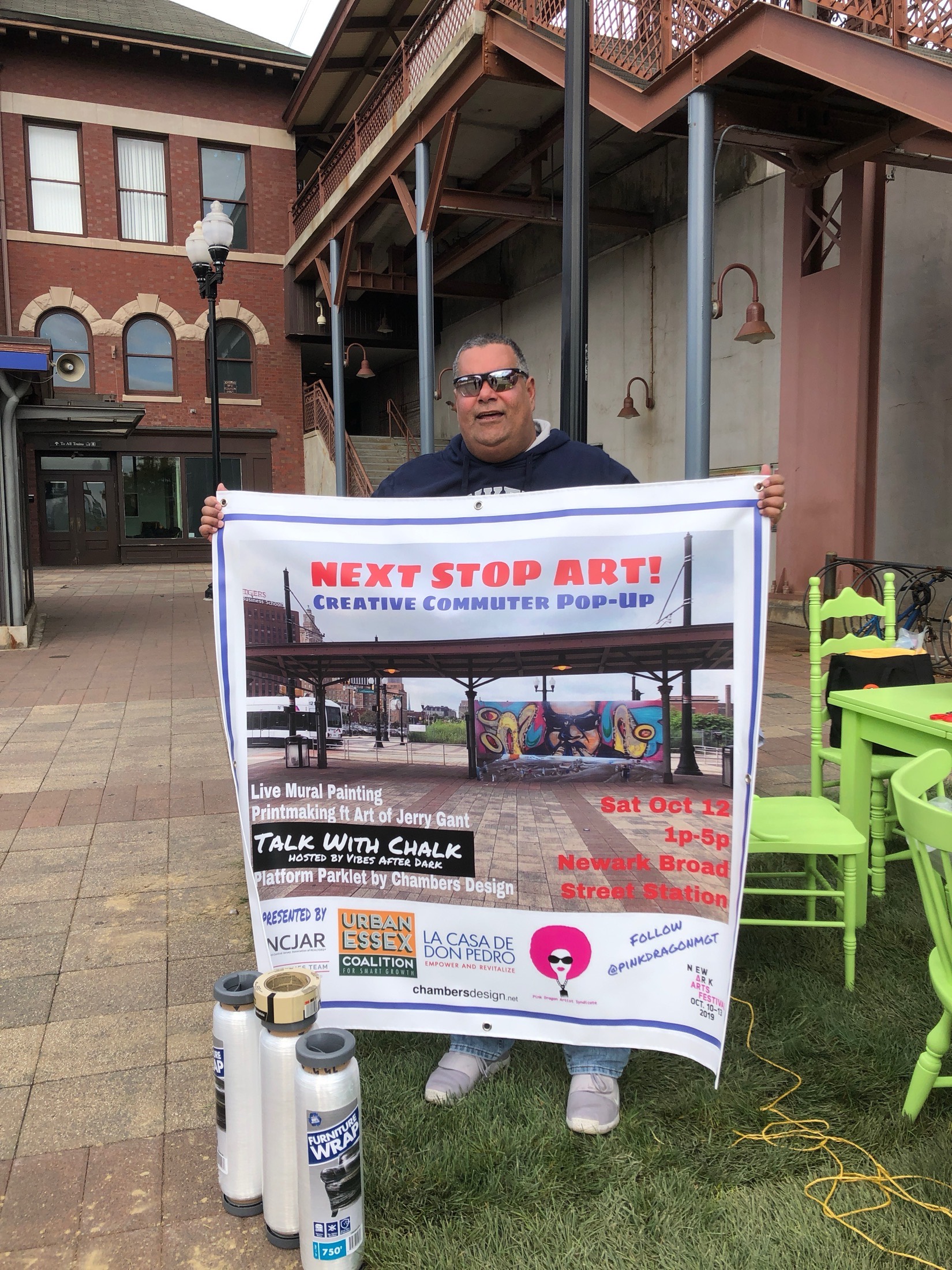 Volunteer holding the Next Stop Art event promo banner