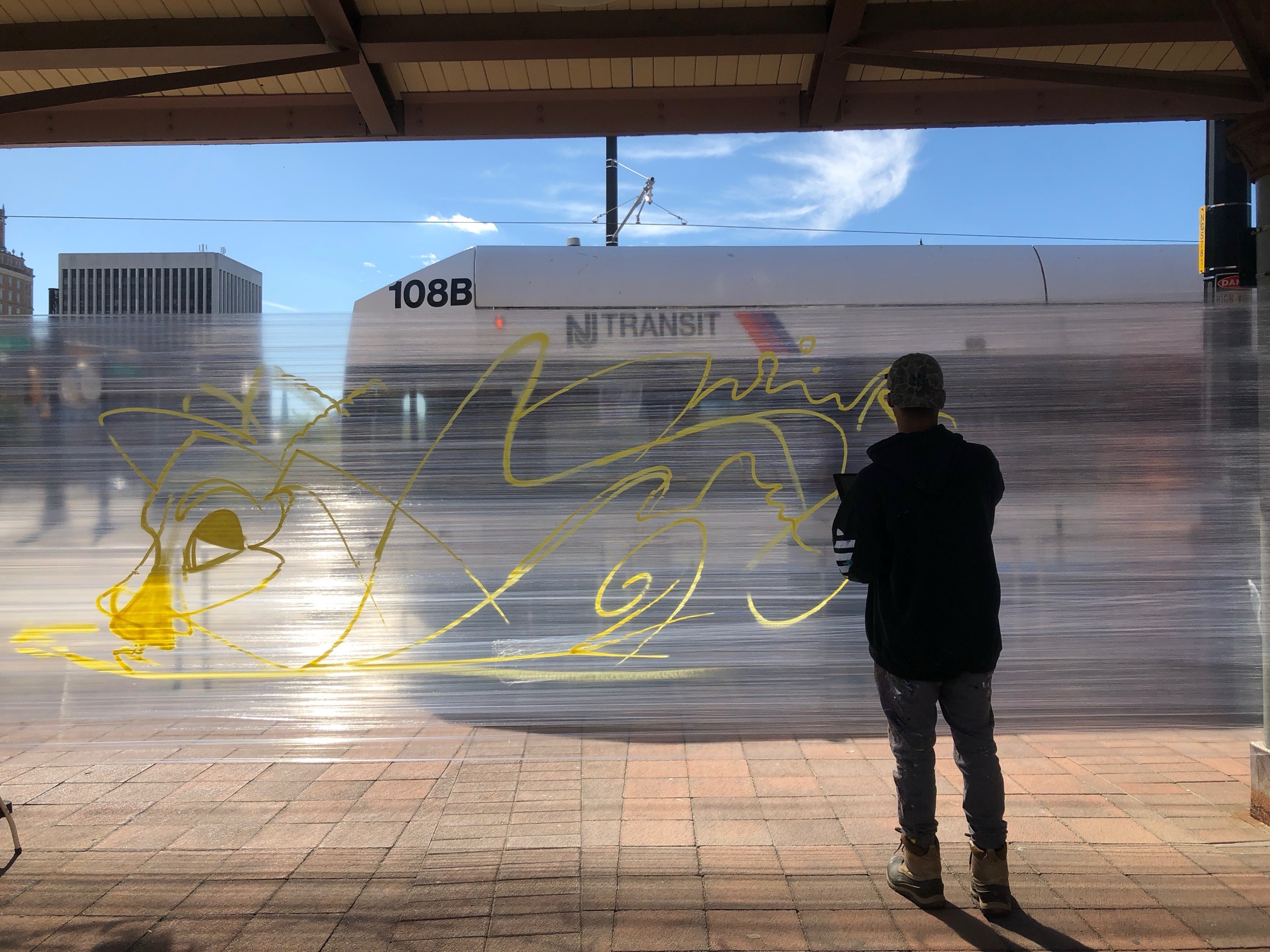 Artist sketching a mural outline on a station enclosure