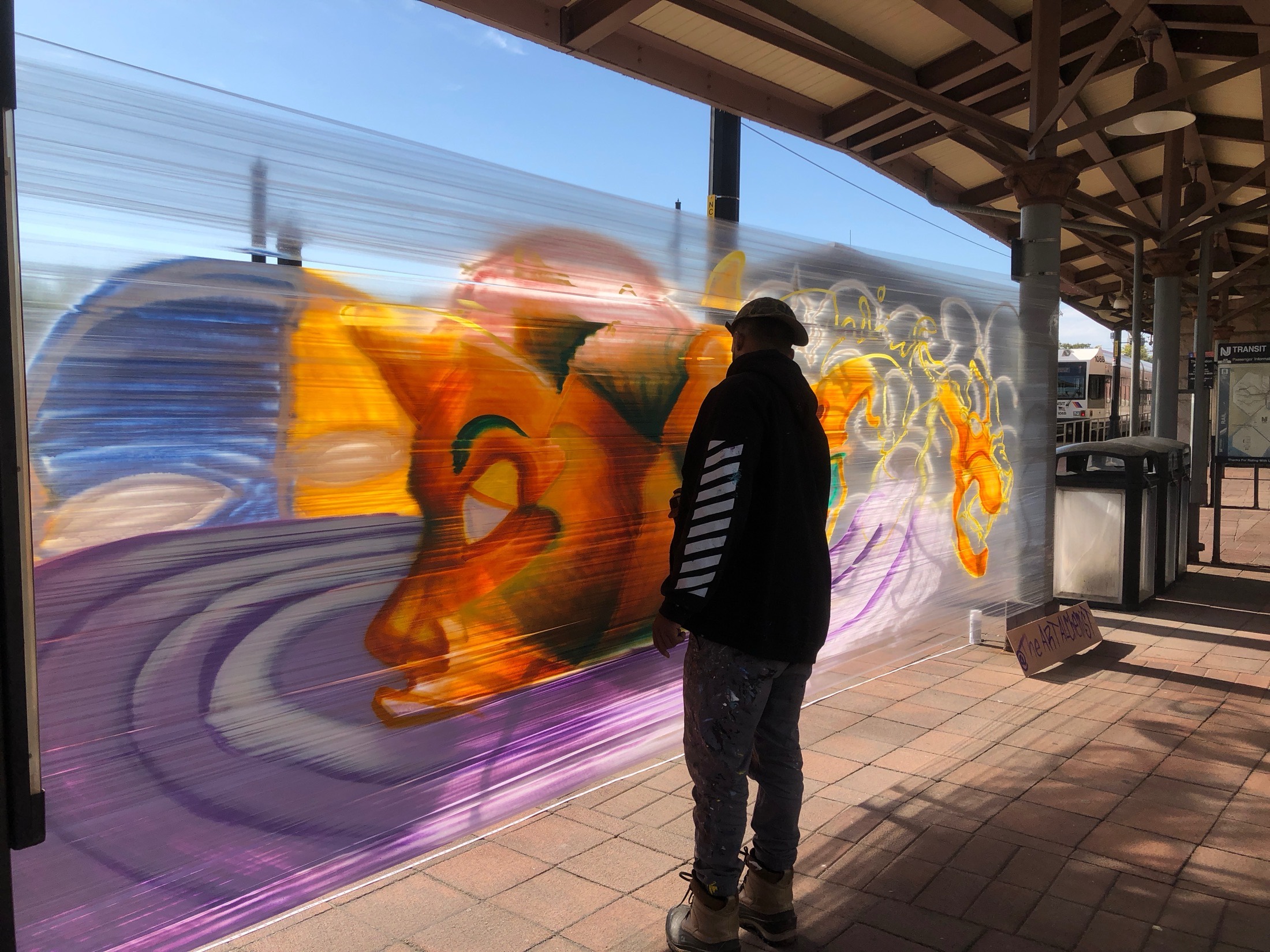 Steve Green painting a colorful tiger mural at Broad Street Station