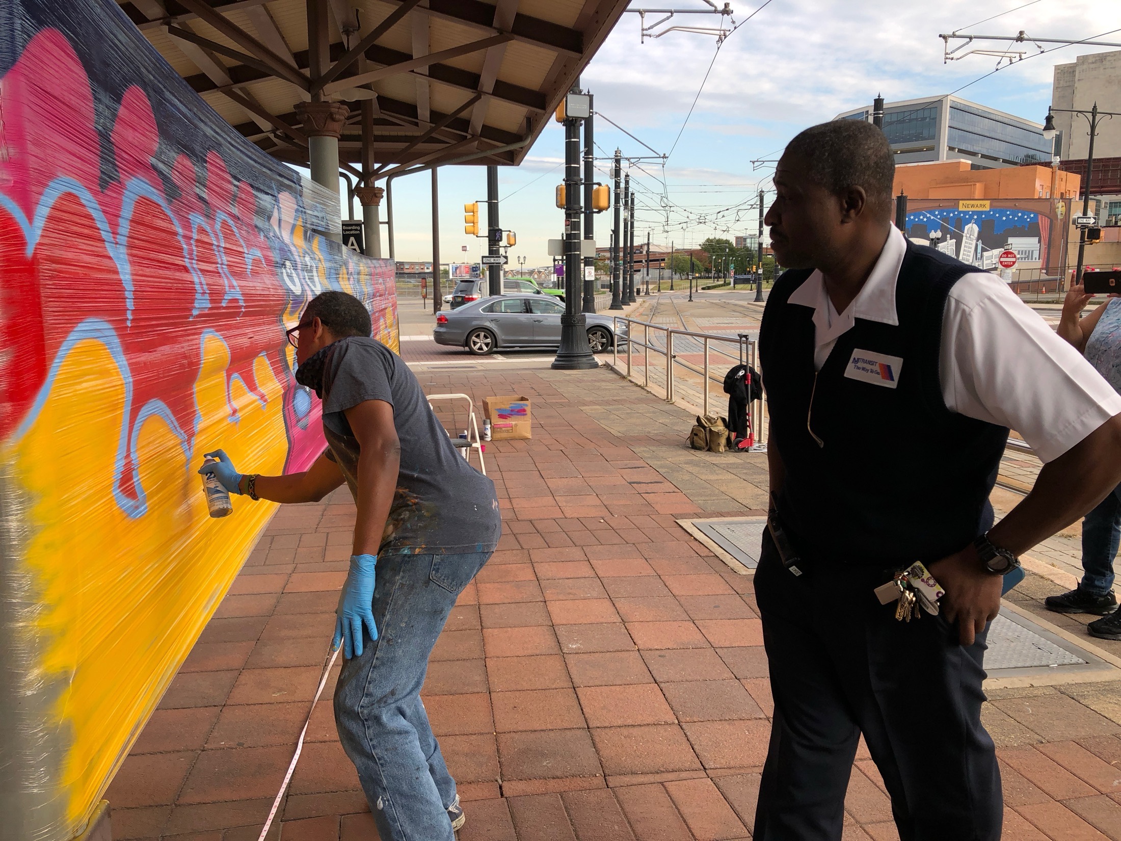 NJ Transit staff watching a muralist paint live at Broad Street Station