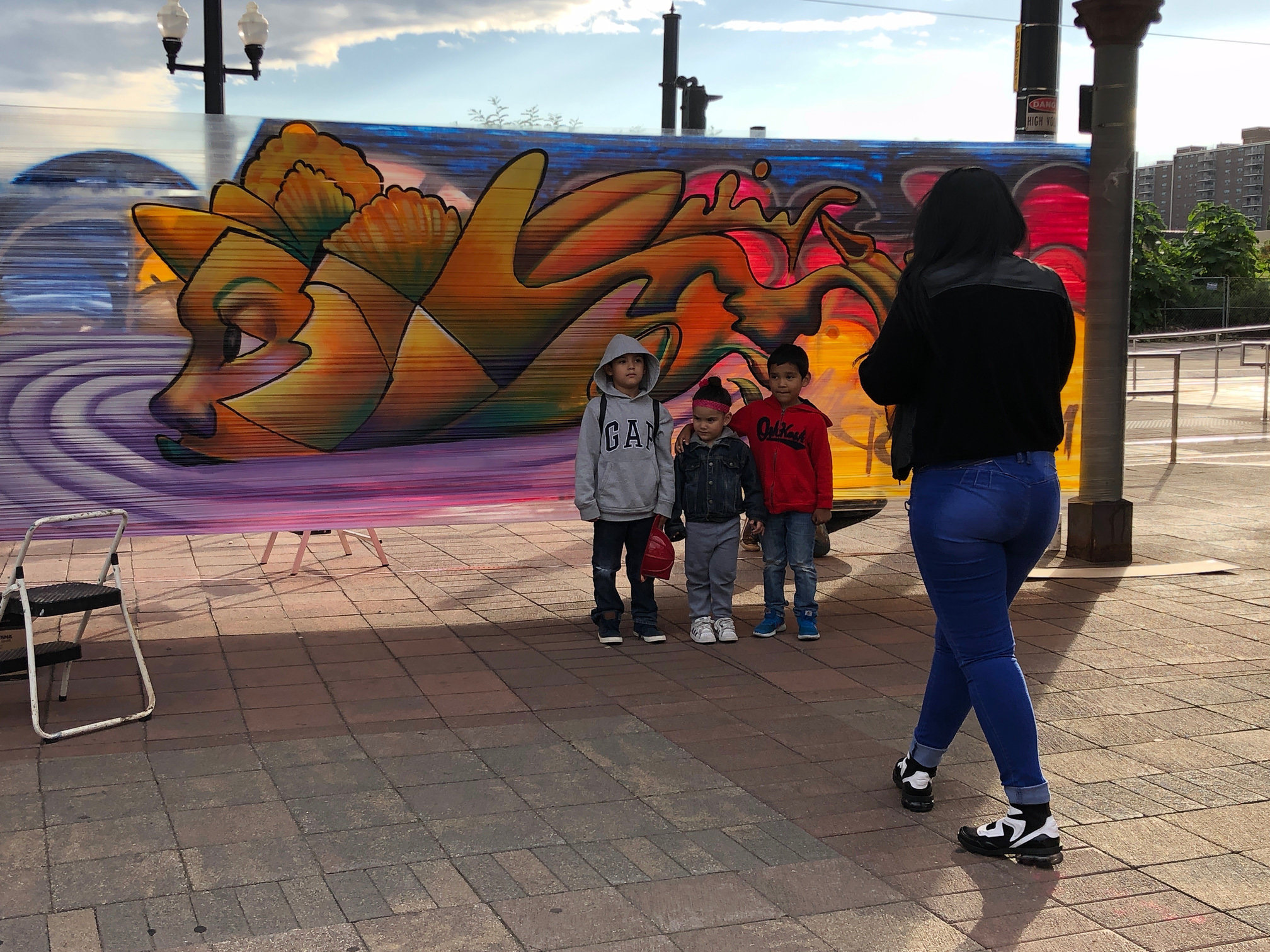 Children posing in front of a mural at a community art event